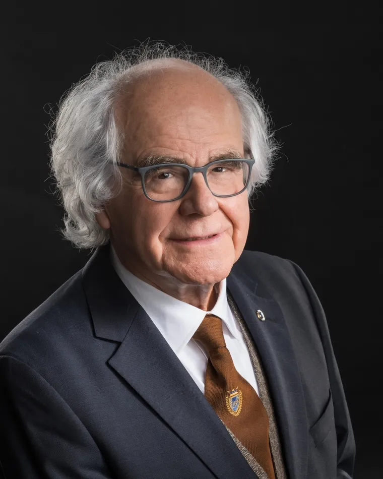 Heinz Lechner, Unternehmer, lächelnd im dunklen Sakko mit brauner Krawatte vor schwarzem Hintergrund