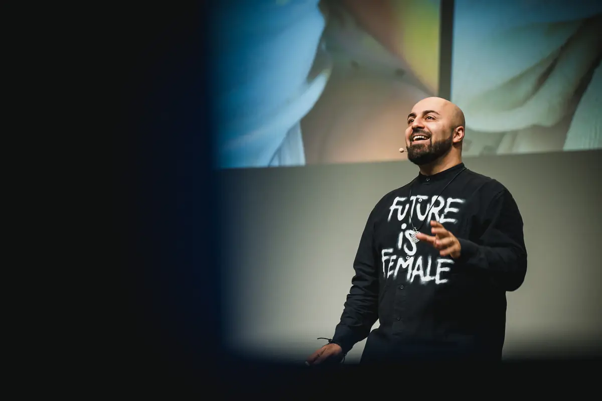 Ali Mahlodji auf der Bühne, im Pullover mit der Aufschrift „Future is Female“